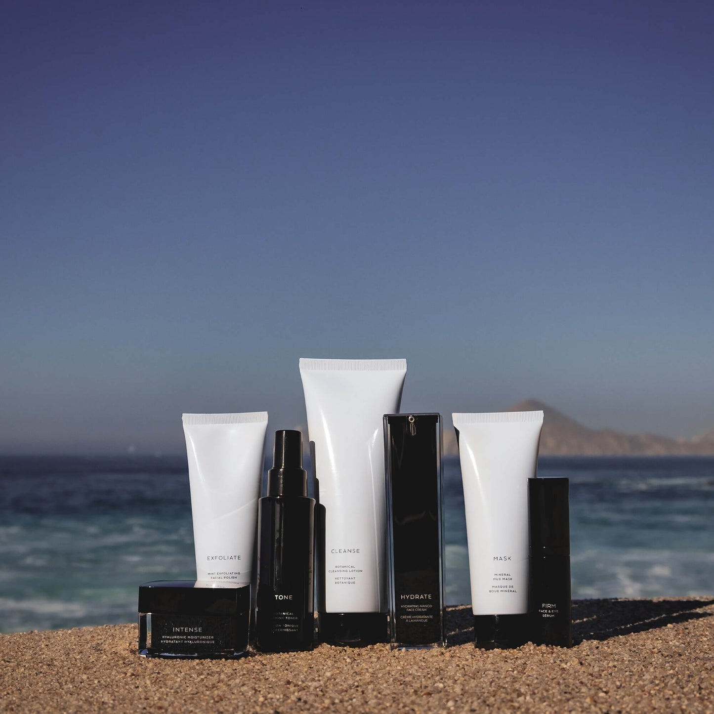 several Rejuva Fresh Brand Skin Care tubes and jars sit on the sand on the beach